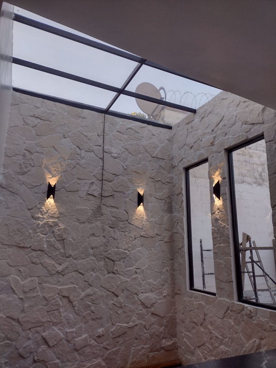 Patio interior con muro de piedra blanca y lámparas